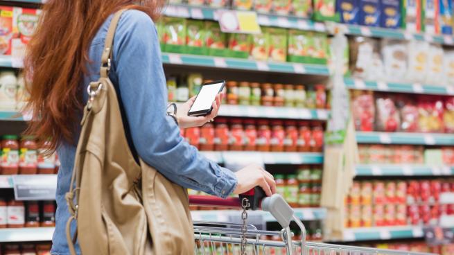 woman shopping in grocery store with phone