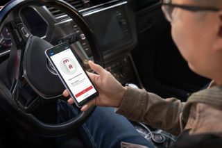 A person in a car holds a phone with Target's drive up return interface.